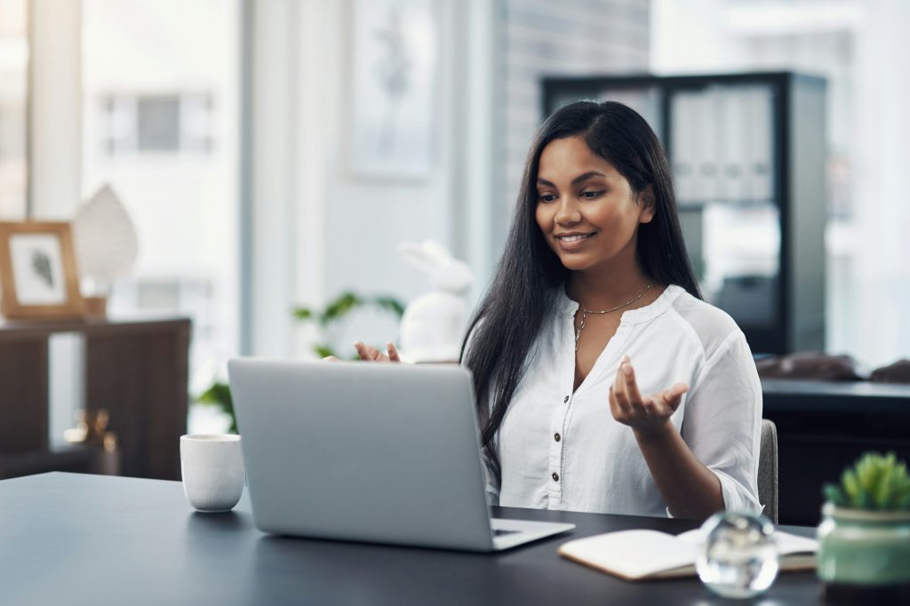 Shot of a young businesswoman making a video call on a laptop in an office